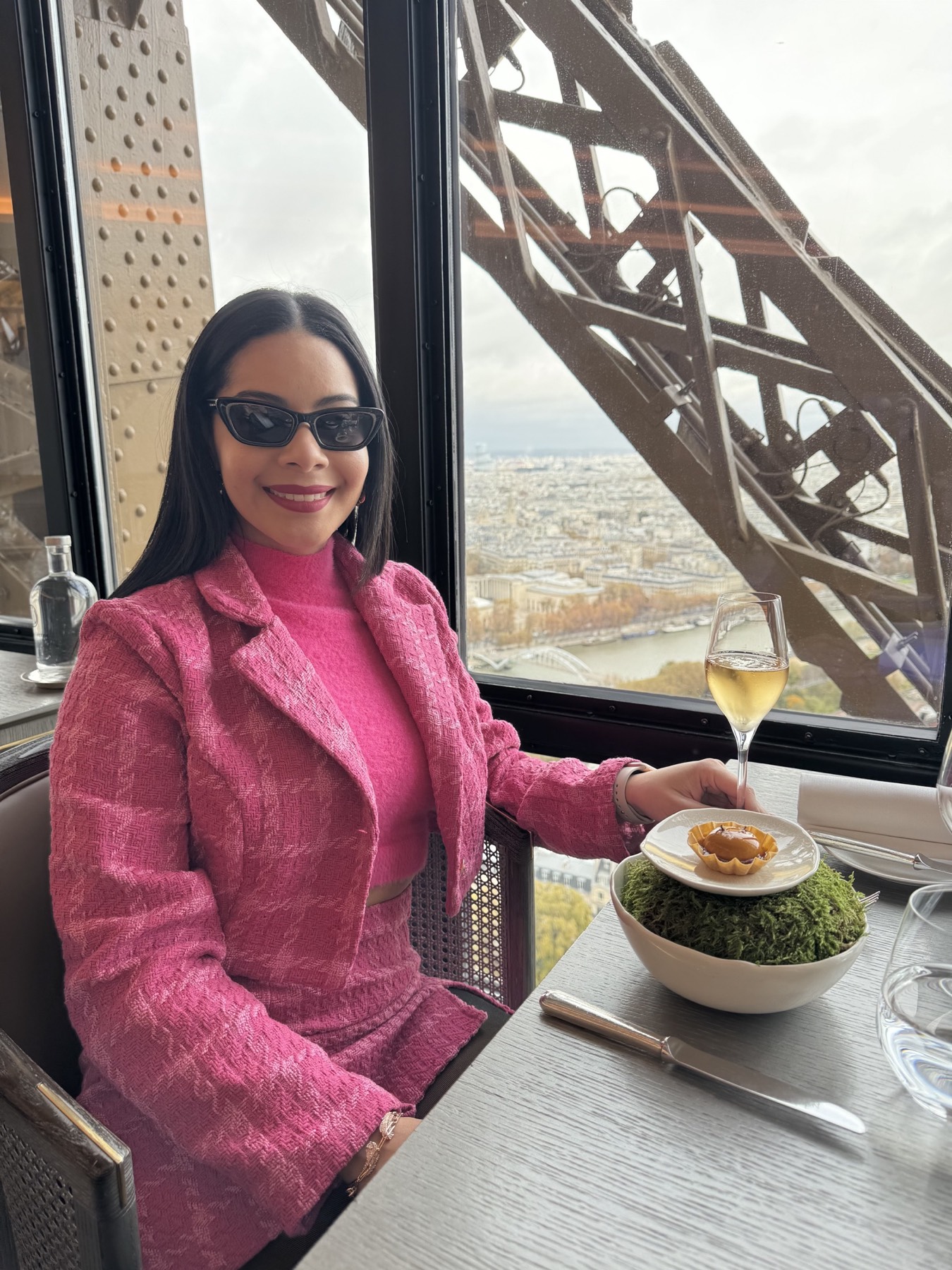 Eliza seated at Le Jules Verne with Paris visible through the Eiffel Tower