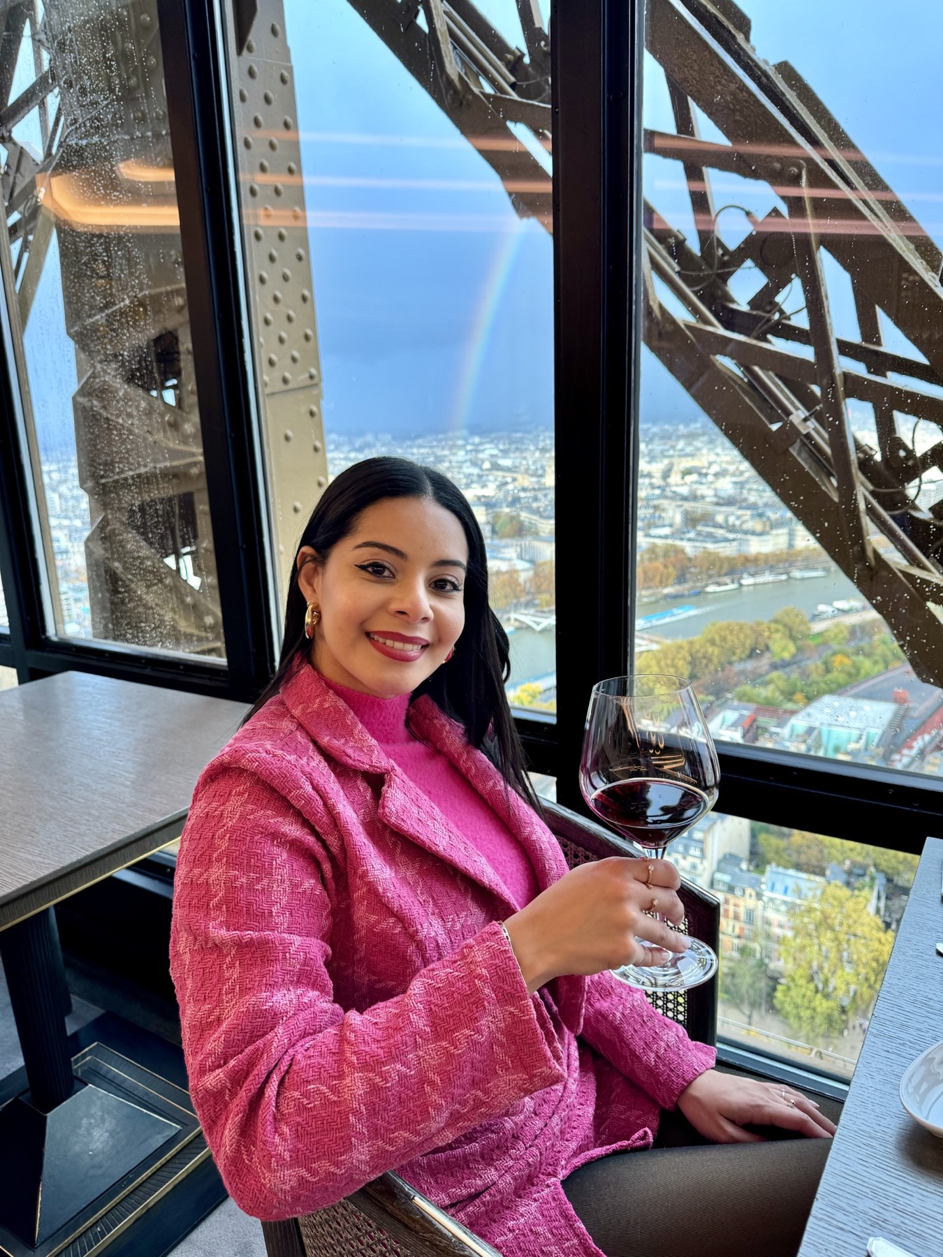 Eliza enjoying wine at Le Jules Verne with a rainbow over Paris