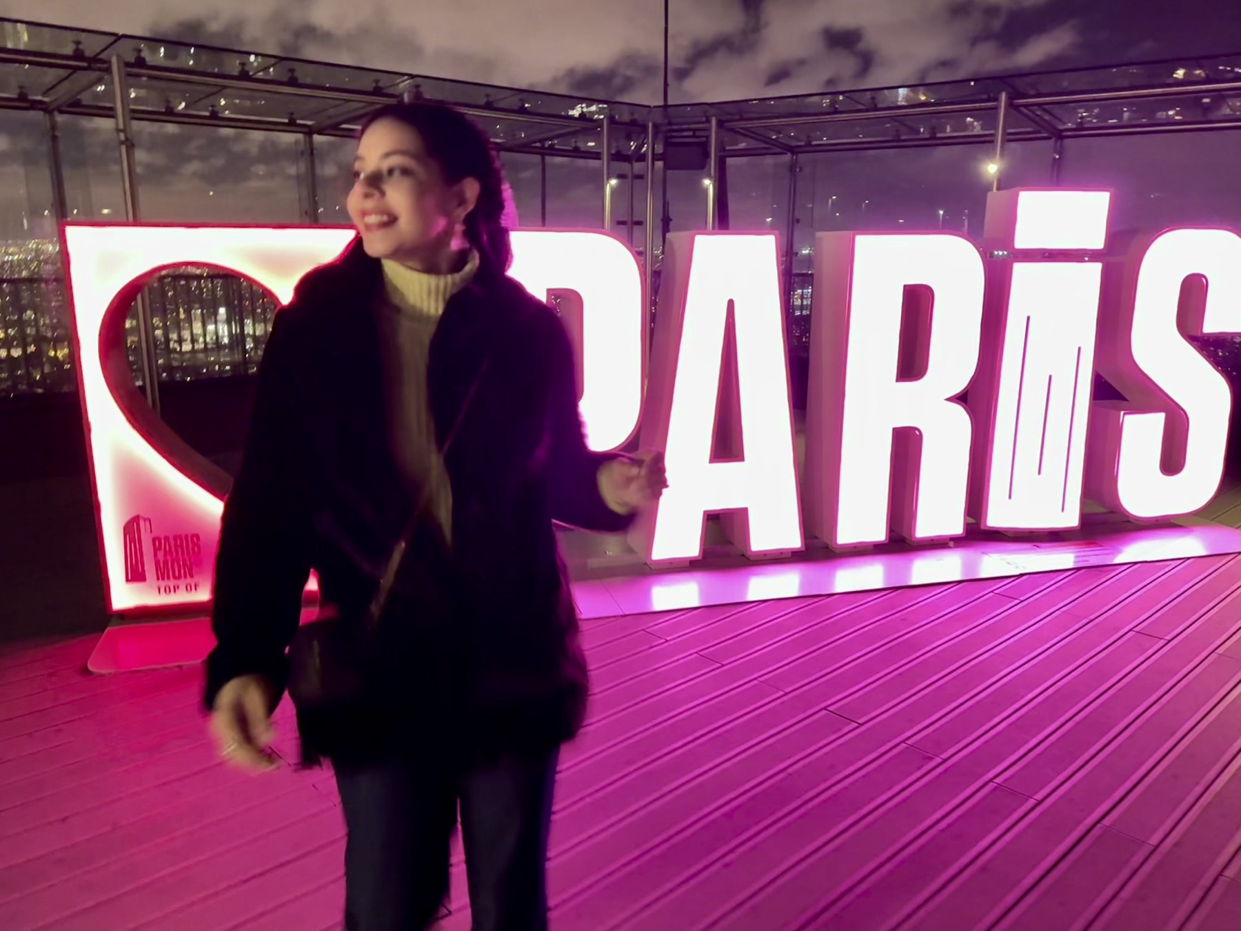 Eliza beside the illuminated Paris sign at Montparnasse Tower