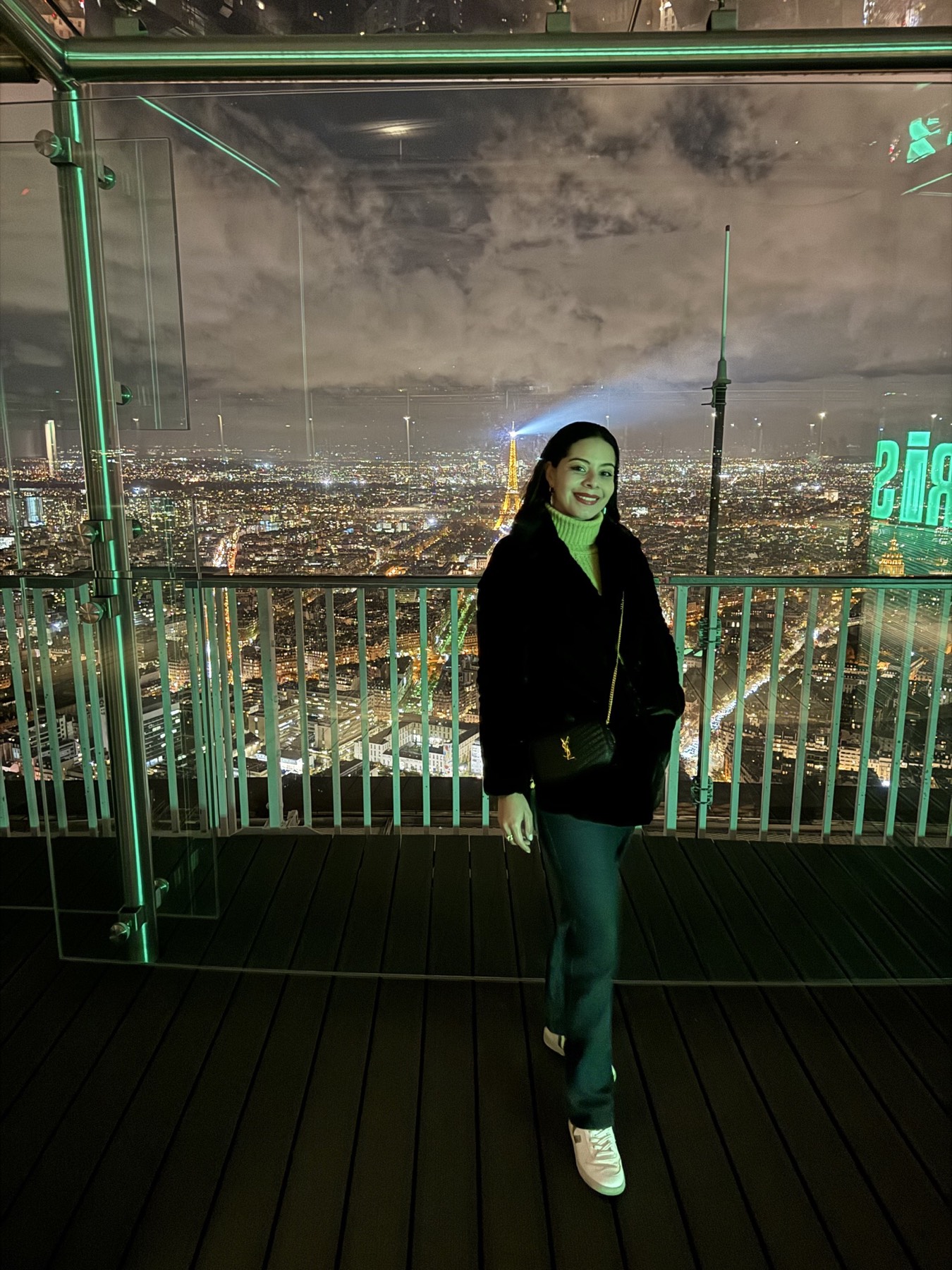 Eliza with the nighttime Paris skyline and Eiffel Tower behind her
