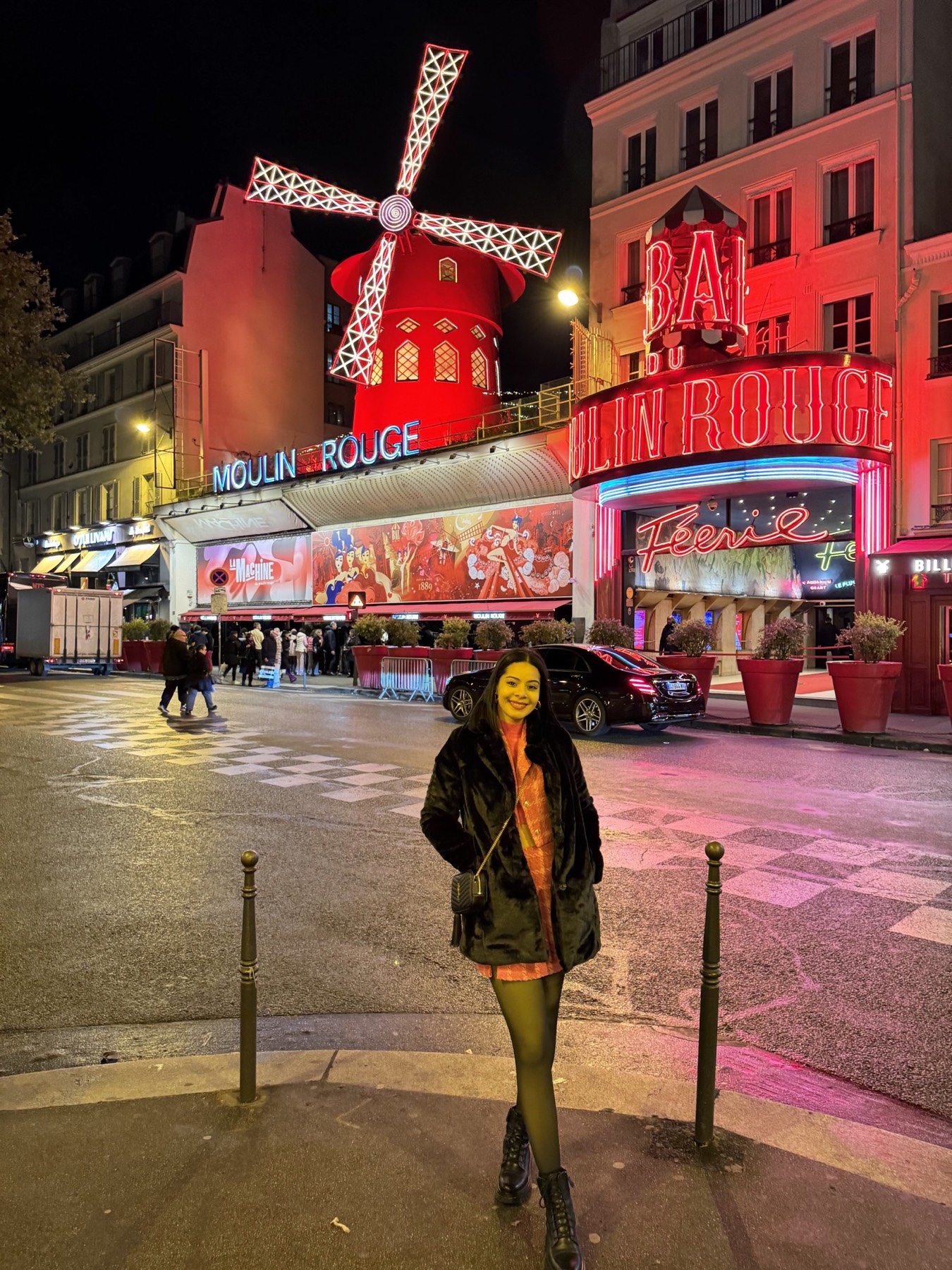 Eliza outside the illuminated Moulin Rouge at night